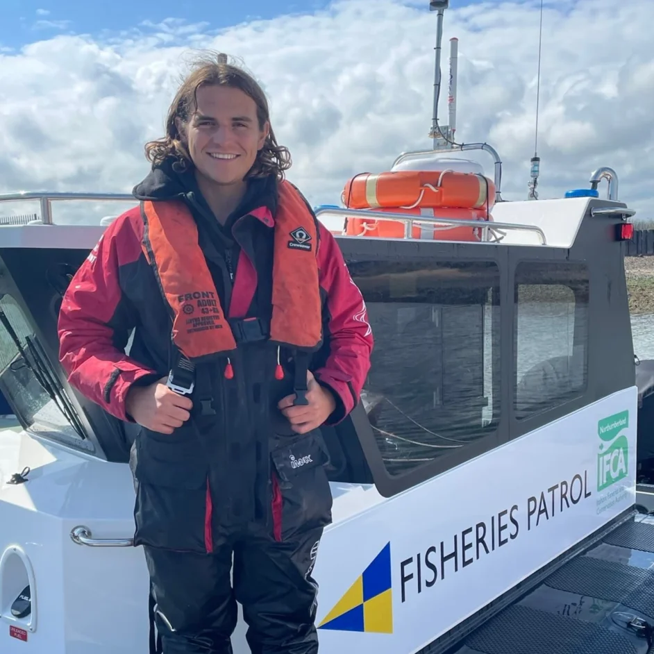 Newcastle University student stood smiling aboard a Fisheries Patrol boat.