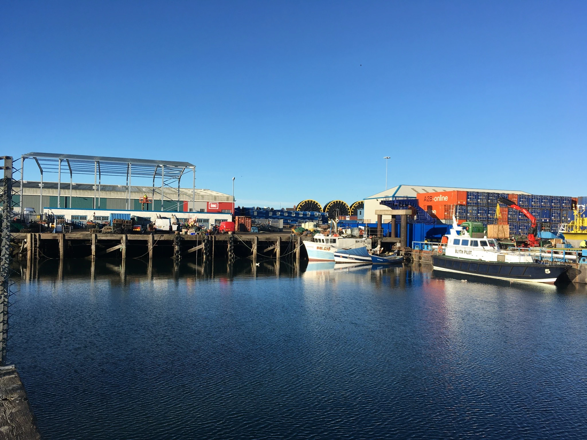 Industrial quayside on sunny day with commercial fishing boats.