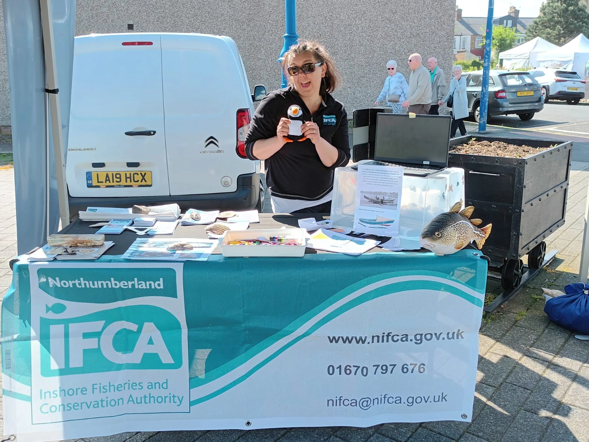 NIFCA representative holding puffin at Amble Puffin Festival behind NIFCA stall.