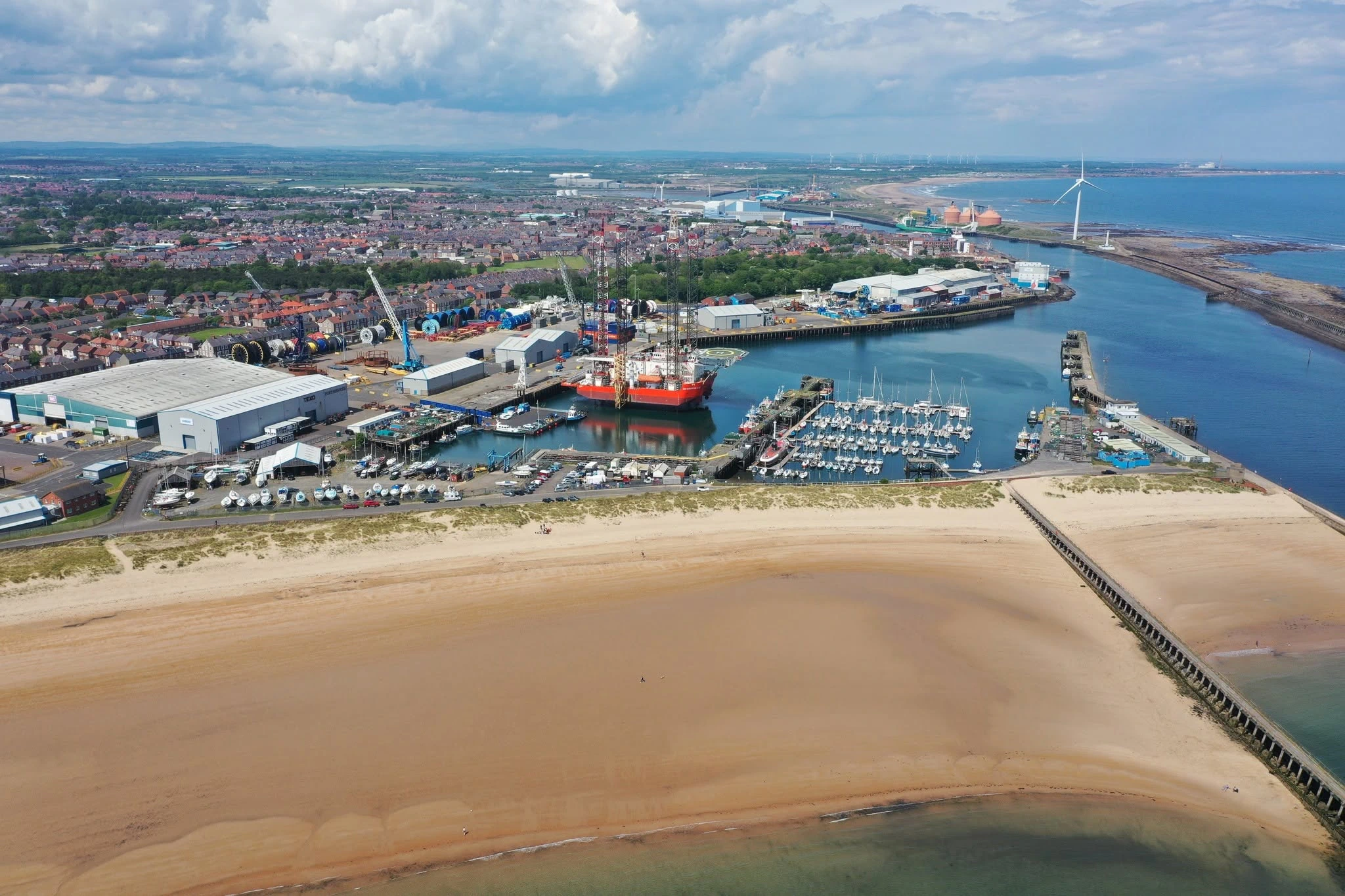 An aerial drone photograph of a busy coastal port and industrial harbour.